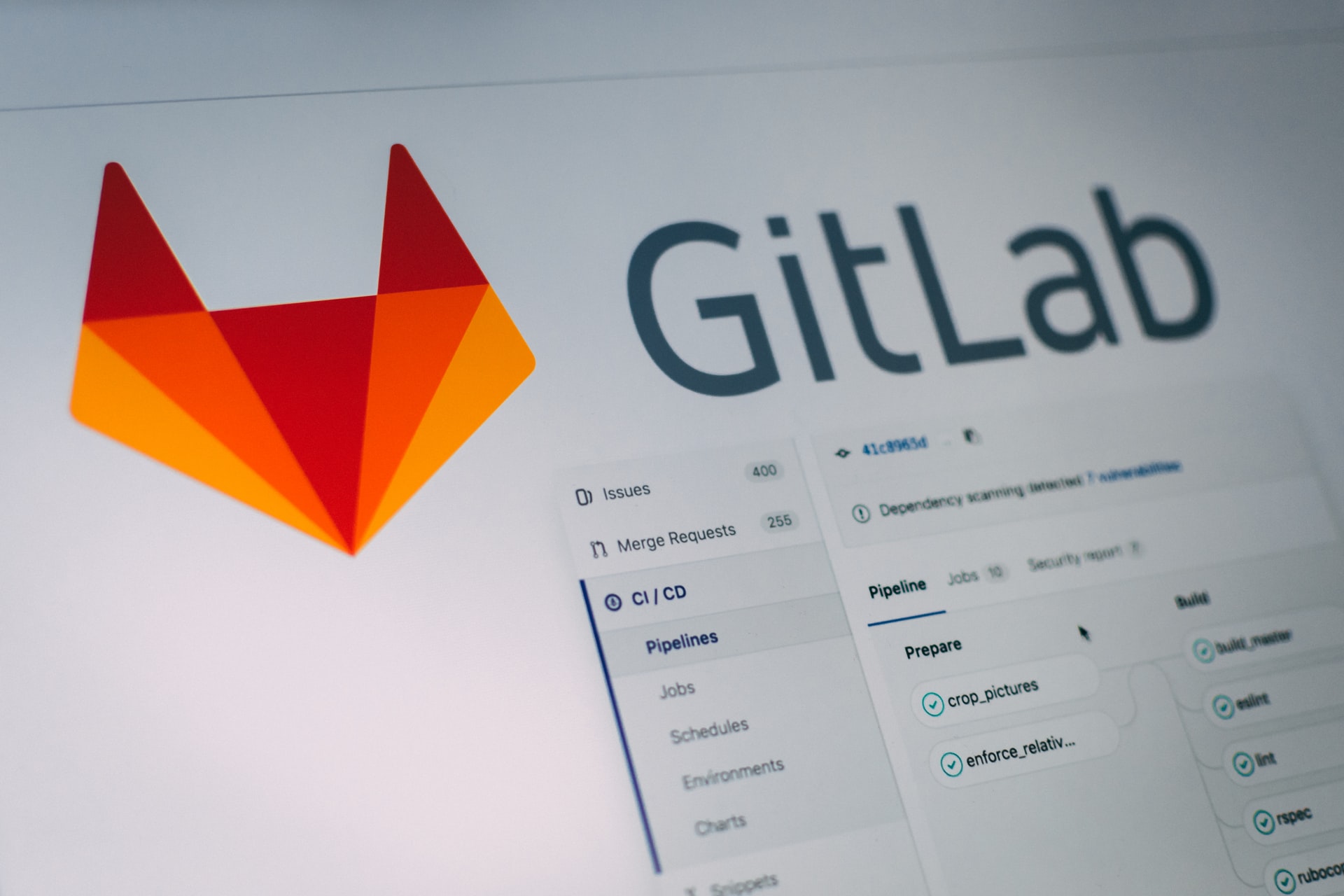 Large Gitlab logo sitting over screenshot of application UI